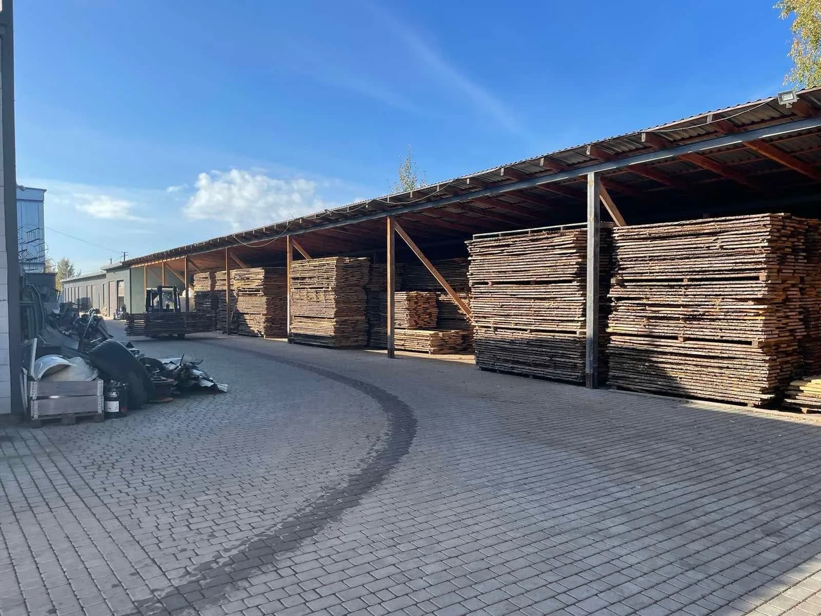Überdachtes Holzlager mit gestapeltem Eichenholz